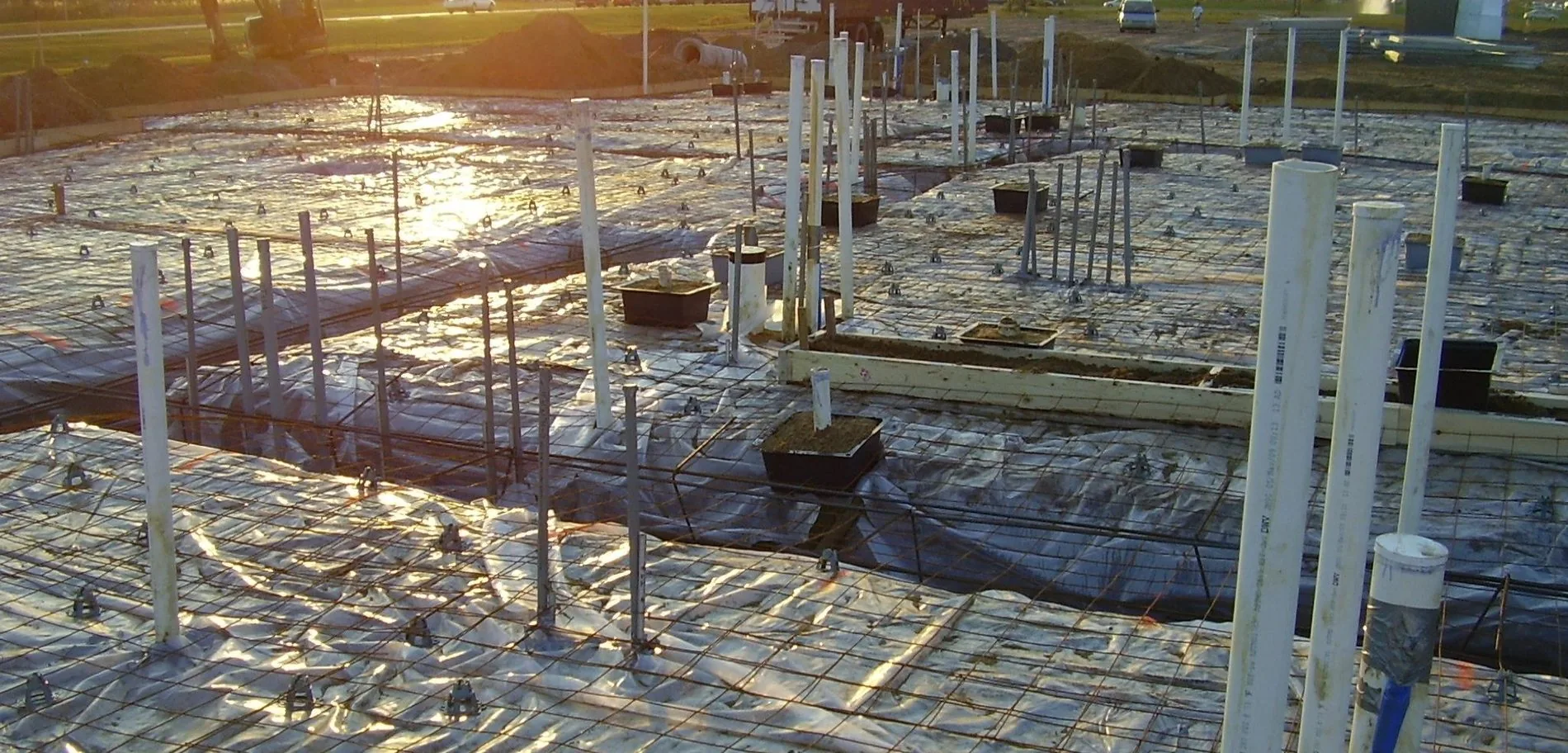 Reinforcing steel and vapor barrier laid out across a commercial slab at sunset
