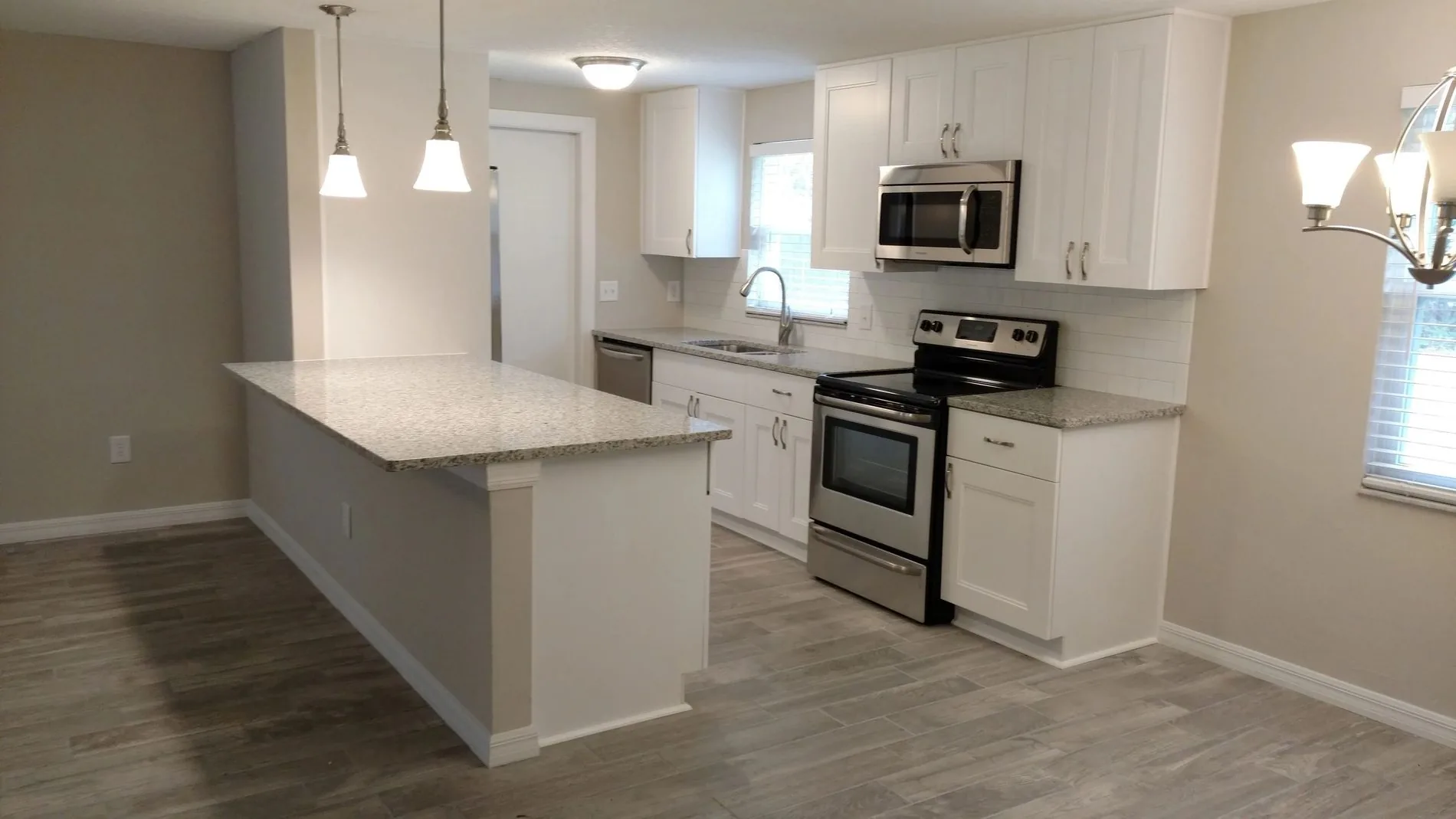 A finished kitchen with a quartz island, white cabinets and stainless appliances