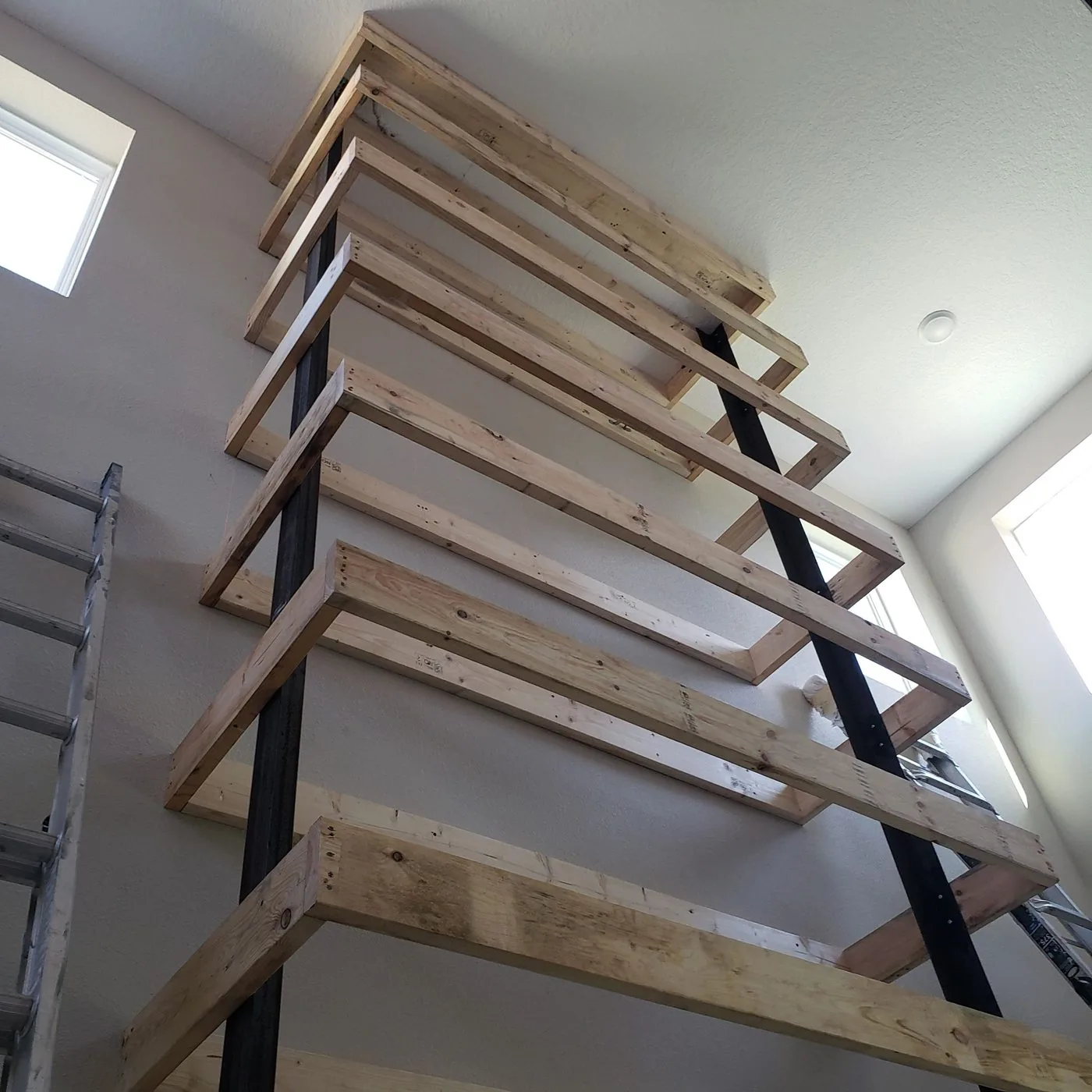 Stair stringers and treads framed against a two-story interior wall